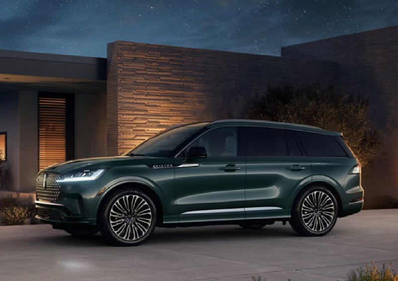 A green 2027 Lincoln Aviator® SUV is parked outside a contemporary home. | Dutch Miller Lincoln of Ashland in Ashland KY