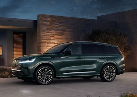 A green 2027 Lincoln Aviator® SUV is parked outside a contemporary home. | Dutch Miller Lincoln of Ashland in Ashland KY