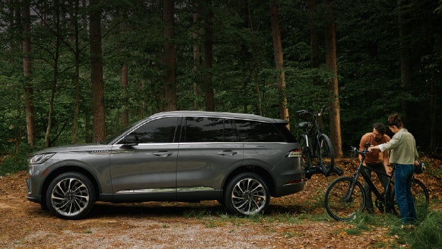 A father and son load e-bikes on a bike rack attached to a 2027 Lincoln Aviator® SUV. | Dutch Miller Lincoln of Ashland in Ashland KY
