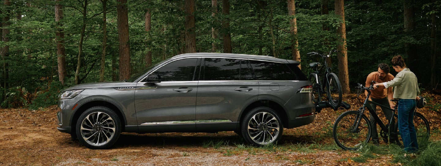A father and son load e-bikes on a bike rack attached to a 2027 Lincoln Aviator® SUV. | Dutch Miller Lincoln of Ashland in Ashland KY
